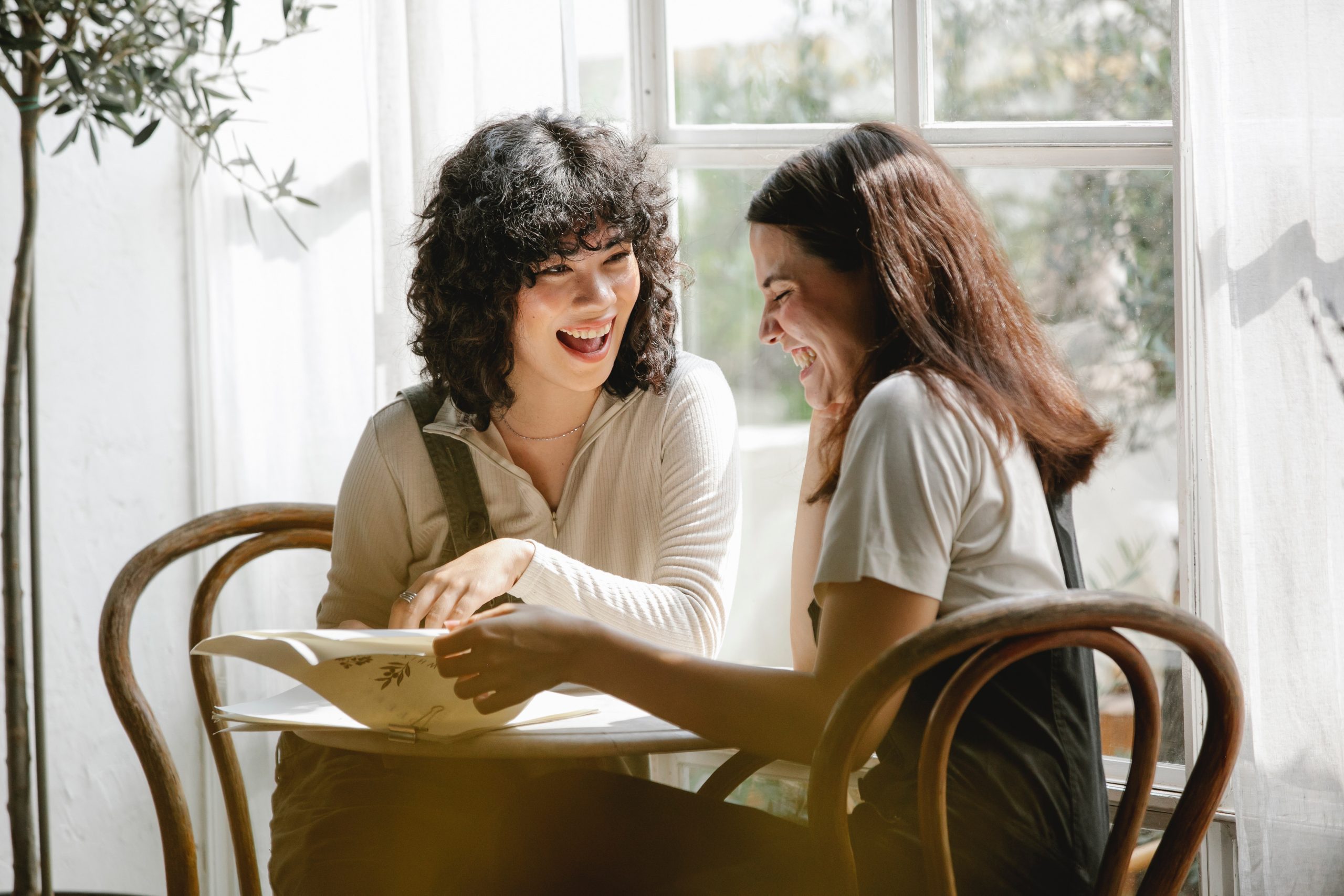 Two women laughing while reading the papers