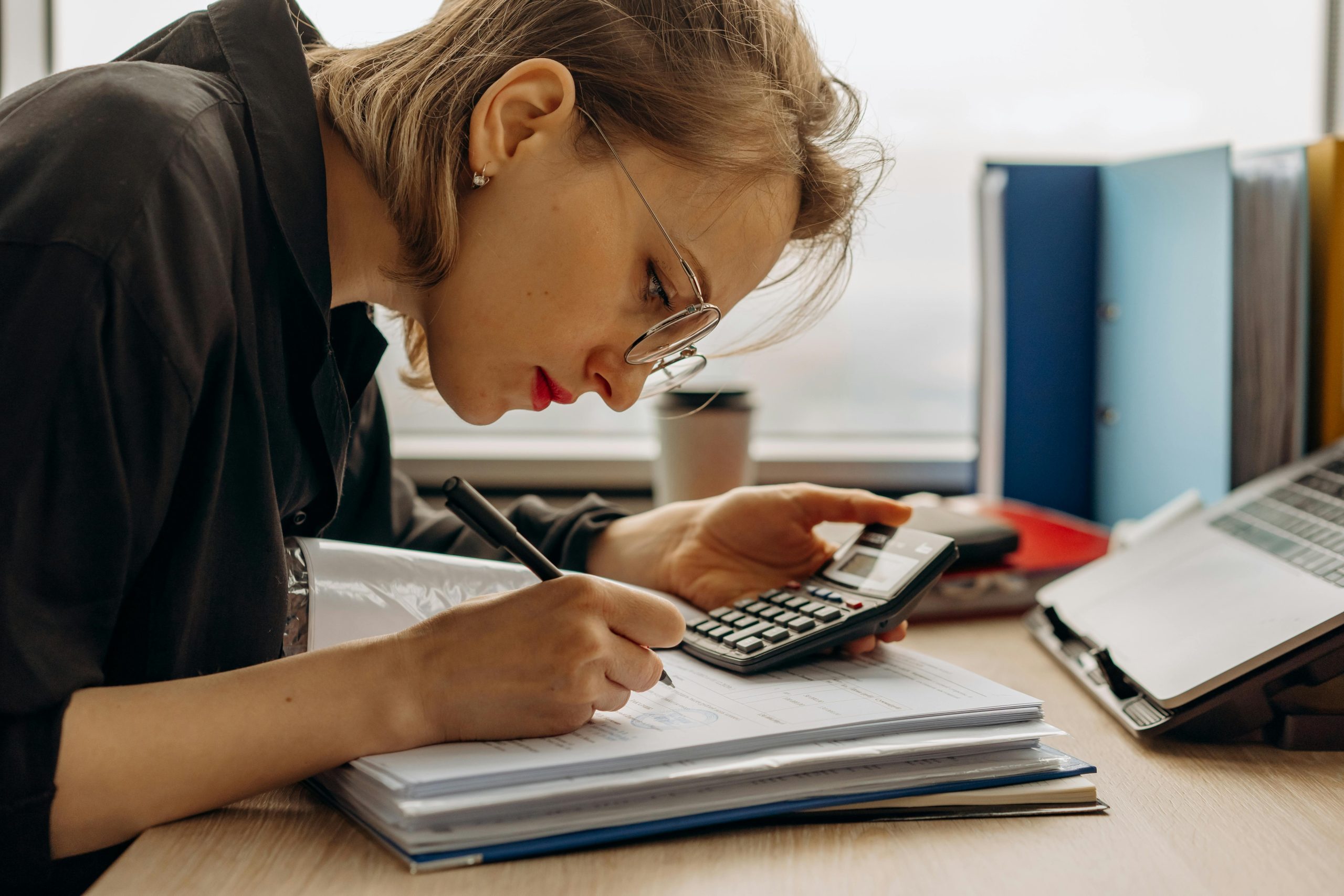 accountant writing and calculating using a calculator