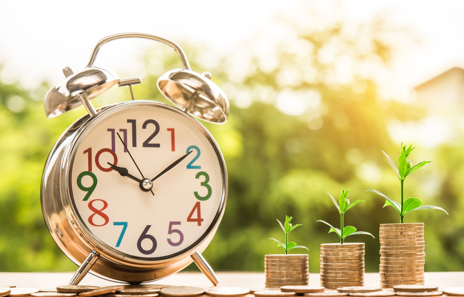 large clock beside stack of coins that is growing