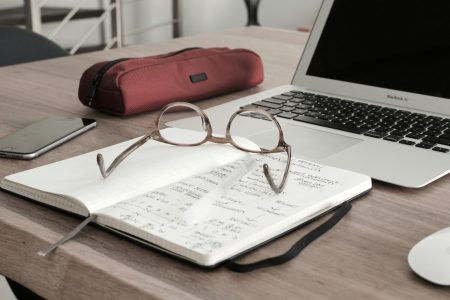 reading glasses on top of a notebook with accounting notes