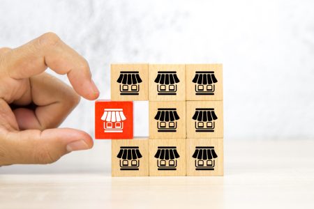 Close-up hand choose wooden block stack with franchise business store icon for franchising to growth branch expansion and business banking loans.