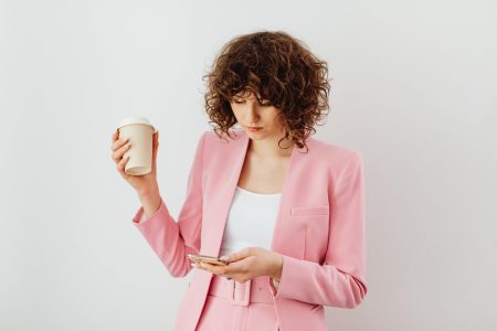 professional tax return accountant holding a coffee cup while watching on her cellphone